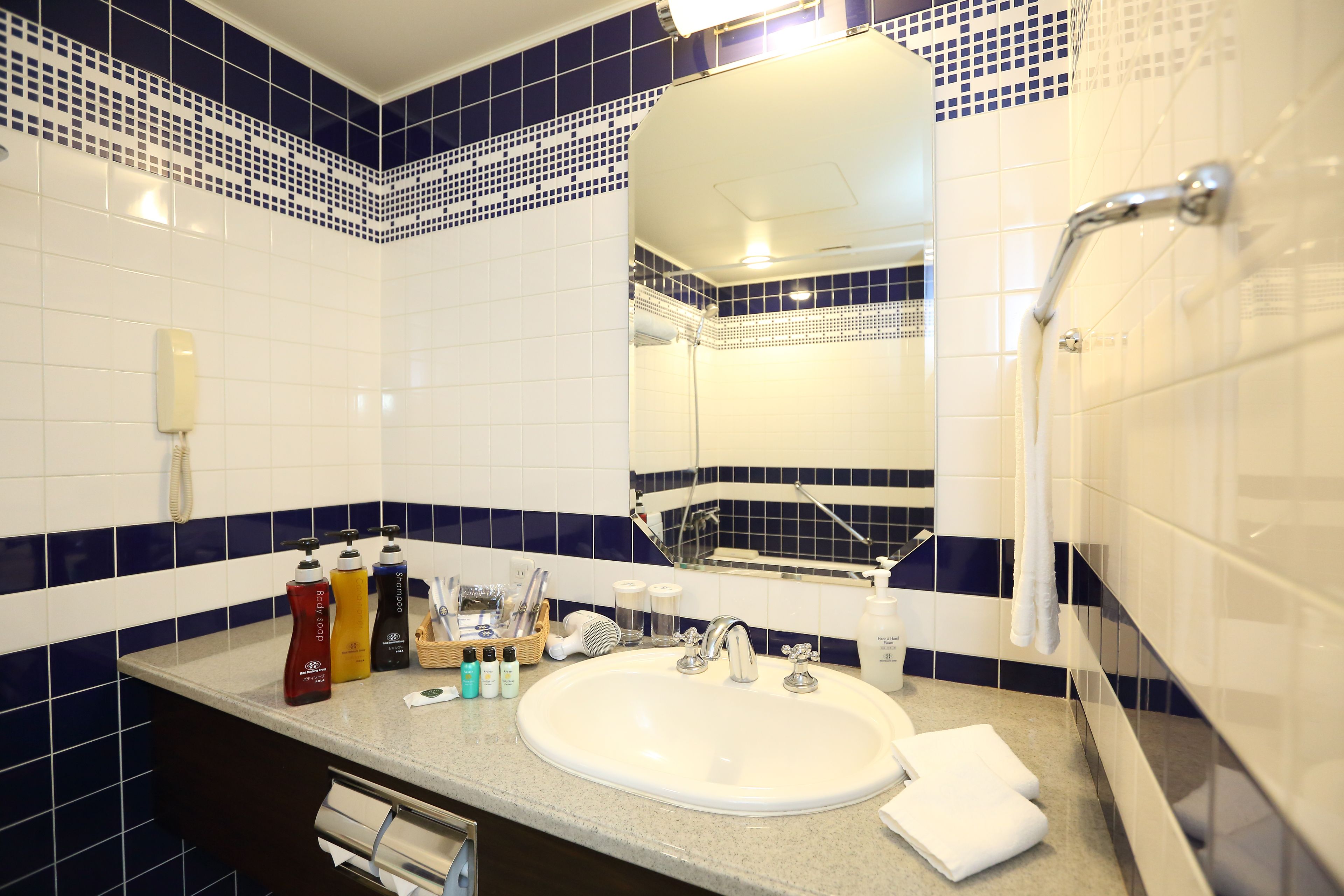 A bathroom with a white sink, a mirror, and a shower. There are toiletries on the counter.