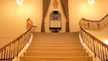 A grand staircase with a curved railing, a decorative wall piece, and a chandelier.