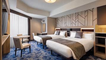 A hotel room with two beds, a desk, a chair, and a TV.
