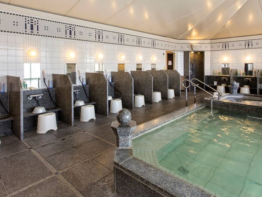 A modern spa with multiple seating areas, a central pool, and a tiled wall with a decorative pattern.