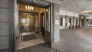 A hotel entrance with a glass door, a reception desk, and a check-in counter.
