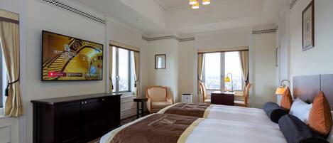 A hotel room with a large bed, a TV mounted on the wall, a desk, and a chair.