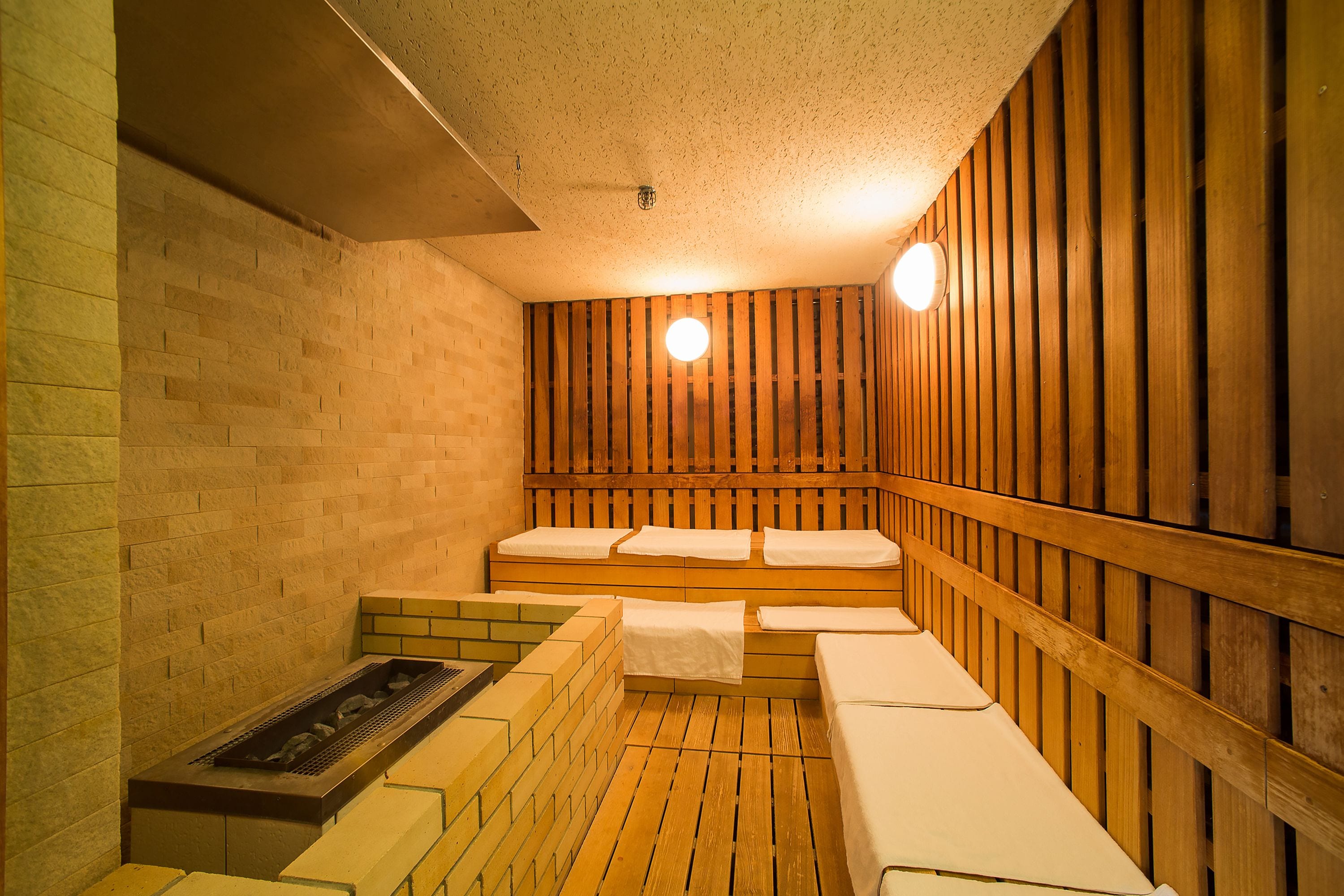 A sauna with wooden benches and a brick wall.