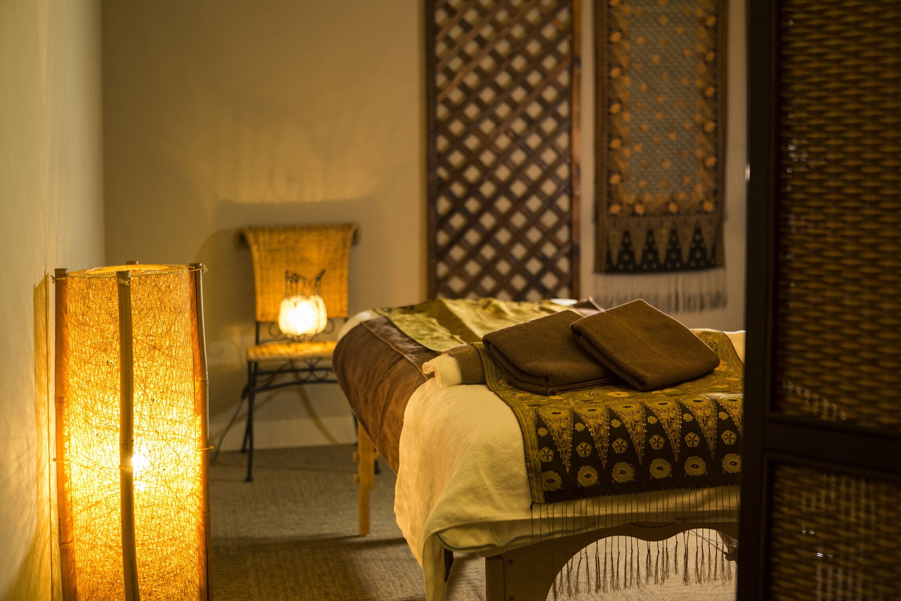 A neatly arranged bedroom with a bed, a chair, and a lamp.