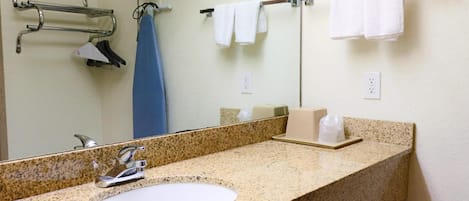 A bathroom with a granite countertop sink, a mirror, a towel rack with white towels, and a soap dispenser.