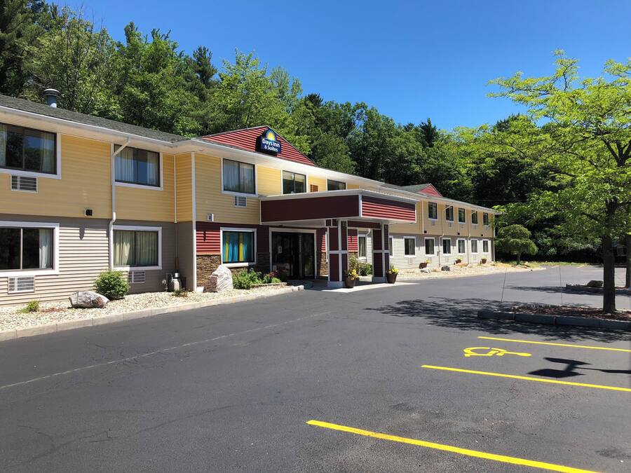 Un motel à plusieurs étages, arborant l’enseigne « Days Inn & Suites », doté d’une entrée couverte et d’un parking comprenant des places réservées aux personnes handicapées.