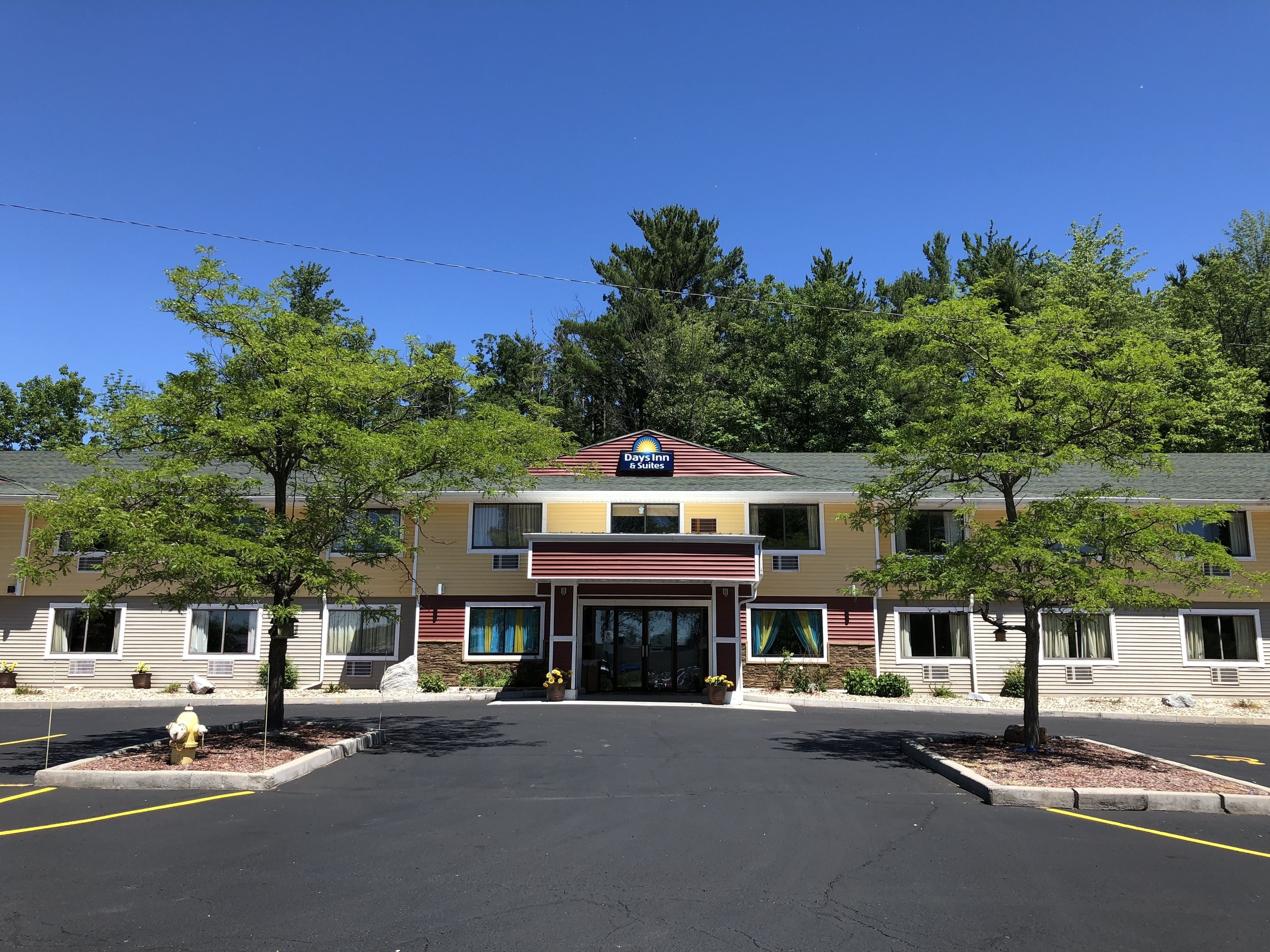 A Days Inn Suites building with a central entrance, surrounded by trees and a parking lot.