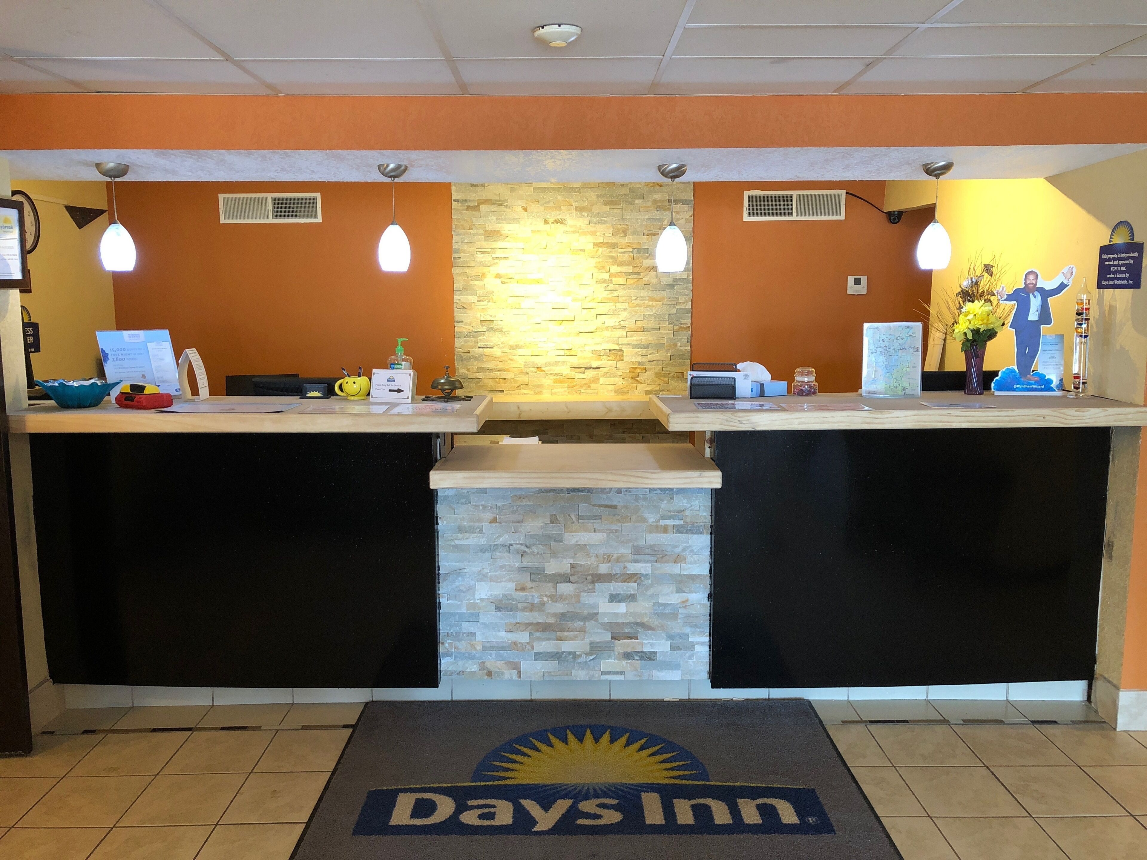 A reception area with a stone wall and two reception counters, each with a light fixture and a small plant.