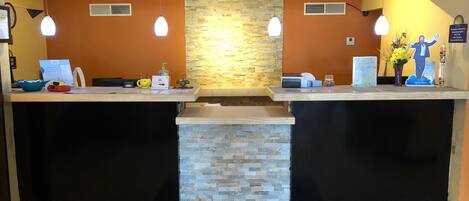 A reception area with a stone wall and two reception counters, each with a light fixture and a small plant.