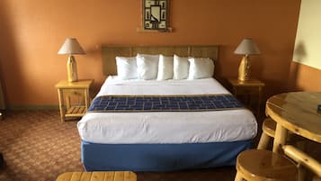 A hotel room with a large bed, two bedside tables with lamps, a small wooden table, and a bench.