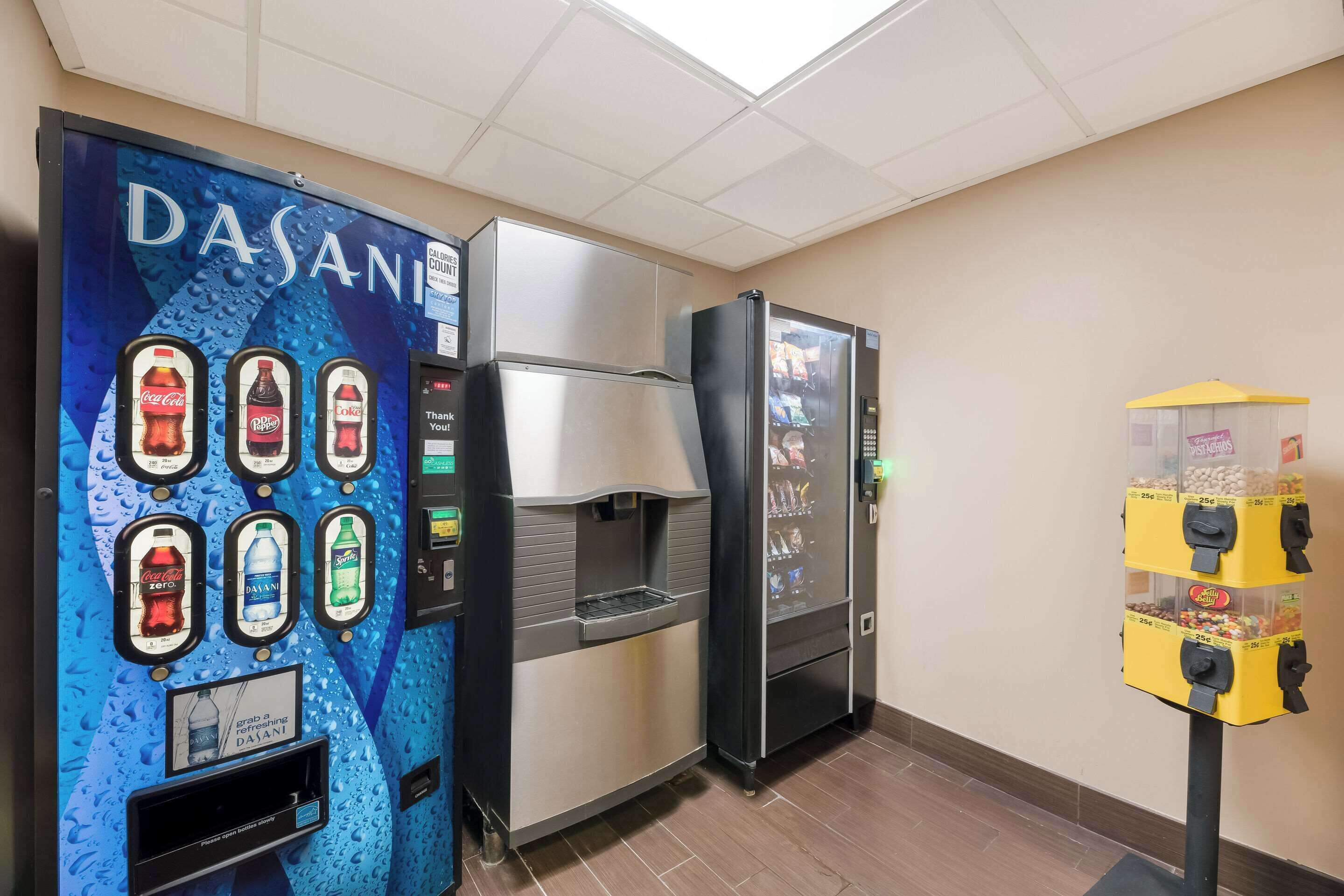 Zona de máquinas expendedoras con dispensador de agua Dasani, un refrigerador y una máquina de aperitivos.