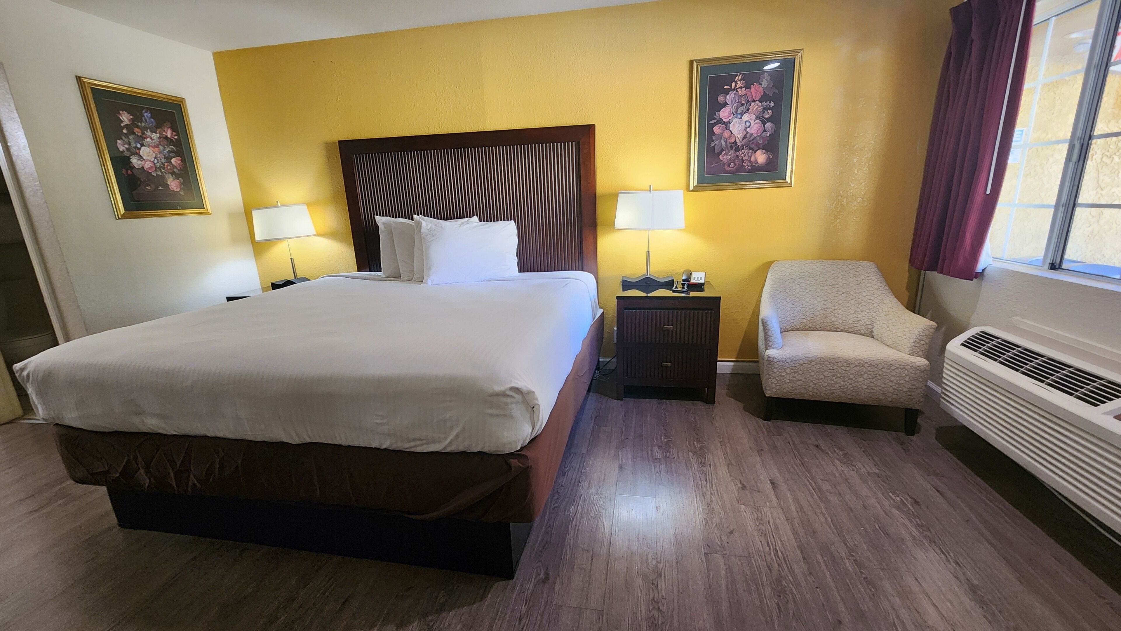 A hotel room with a large bed, two bedside tables with lamps, a chair, and a radiator.