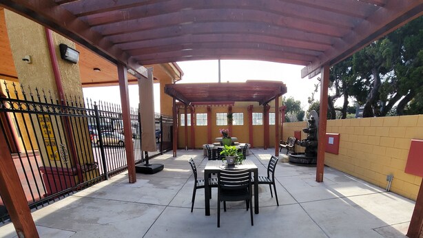 A covered patio area with a table and chairs, a potted plant, and a water feature. - Mission Inn and Suites (Hayward)
