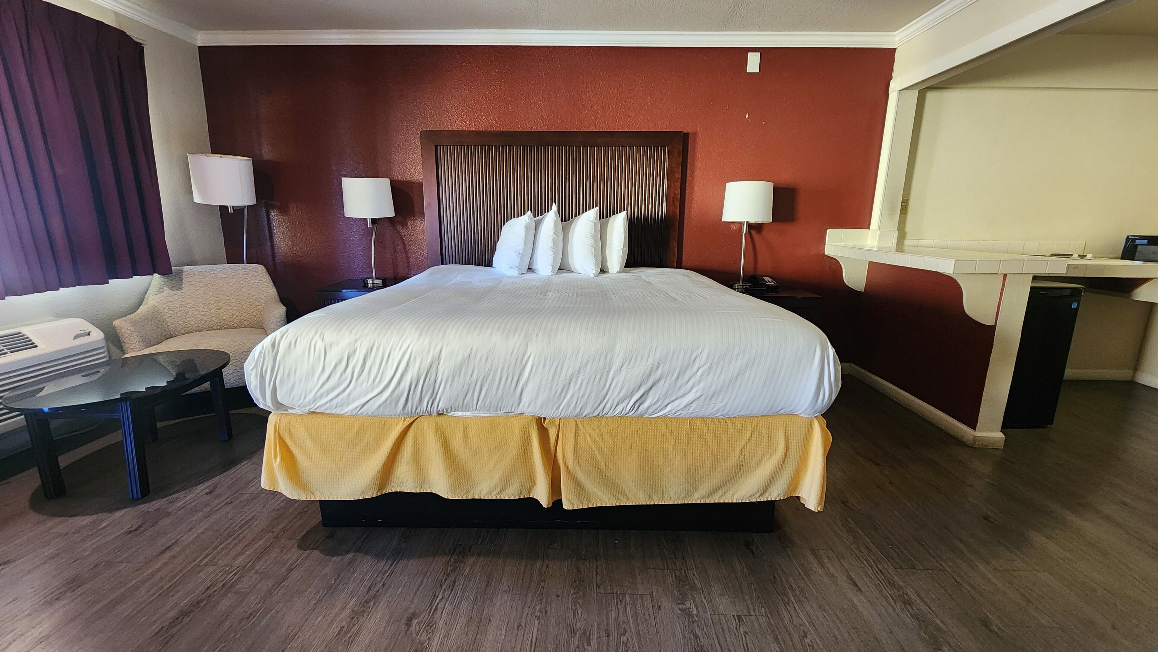 Una camera d'albergo con un letto grande, due comodini, un divano e una scrivania.