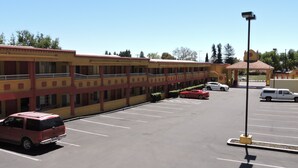 A multi-story hotel with a parking lot. - Mission Inn and Suites (Hayward)