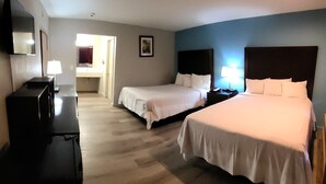 A hotel room with two beds, a desk, a chair, a lamp, and a mirror. - Mission Inn and Suites (Hayward)