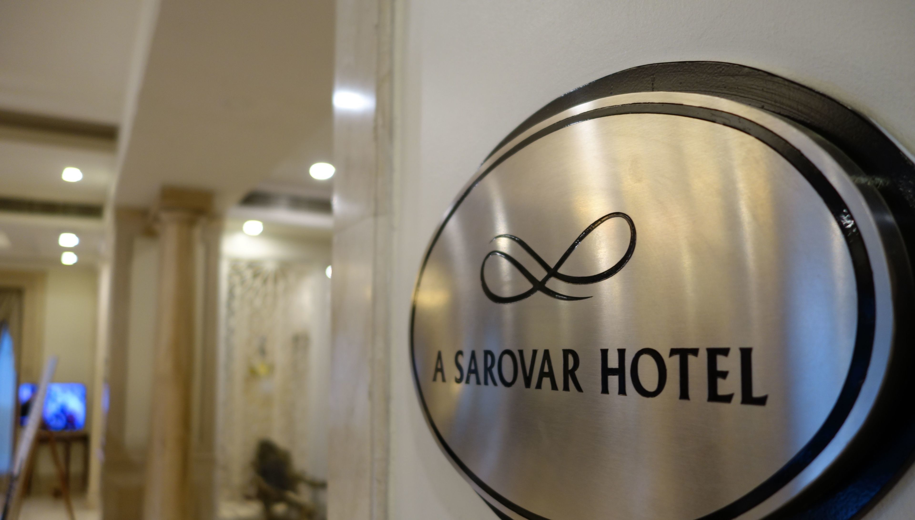 Letrero de A Sarovar Hotel con un símbolo de infinito estilizado sobre el texto.