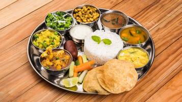 A traditional Indian meal served on a stainless steel plate with various dishes including rice, curry, and vegetables.