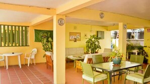 A dining area with yellow walls, green chairs, and a table with a potted plant.