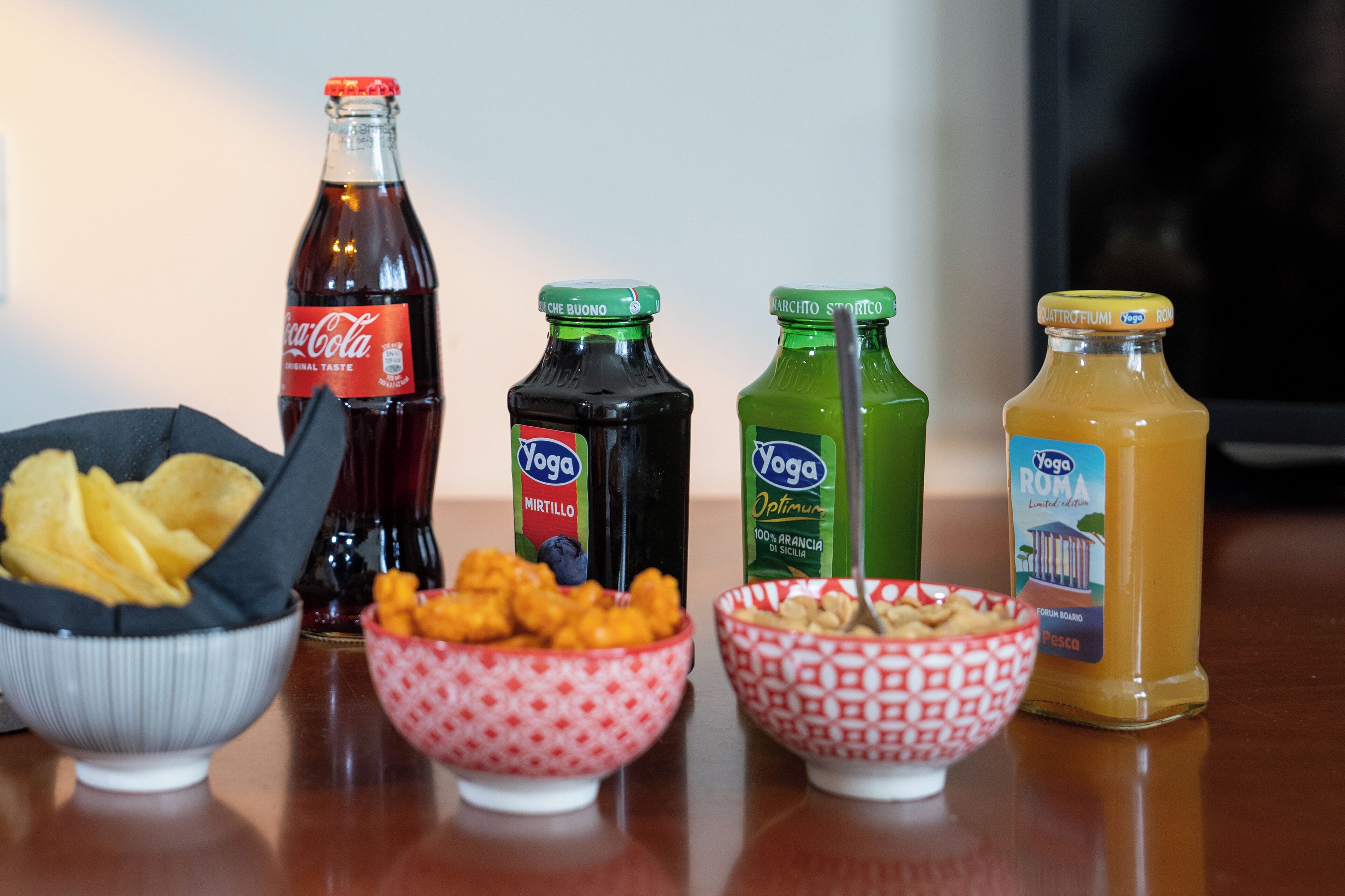 A table with various food items and drinks, including Coca-Cola, Yoga Mirtillo, and Roma juice.