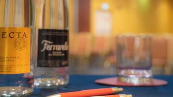 A table with two bottles of water, a glass, and two pens.