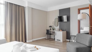 Ett hotellrum med en säng, ett skrivbord, en stol, en tv och en lampa.