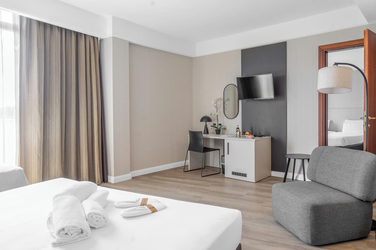 Ein Hotelzimmer mit einem Bett, einem Schreibtisch, einem Sessel, einem Fernseher und einer Lampe.