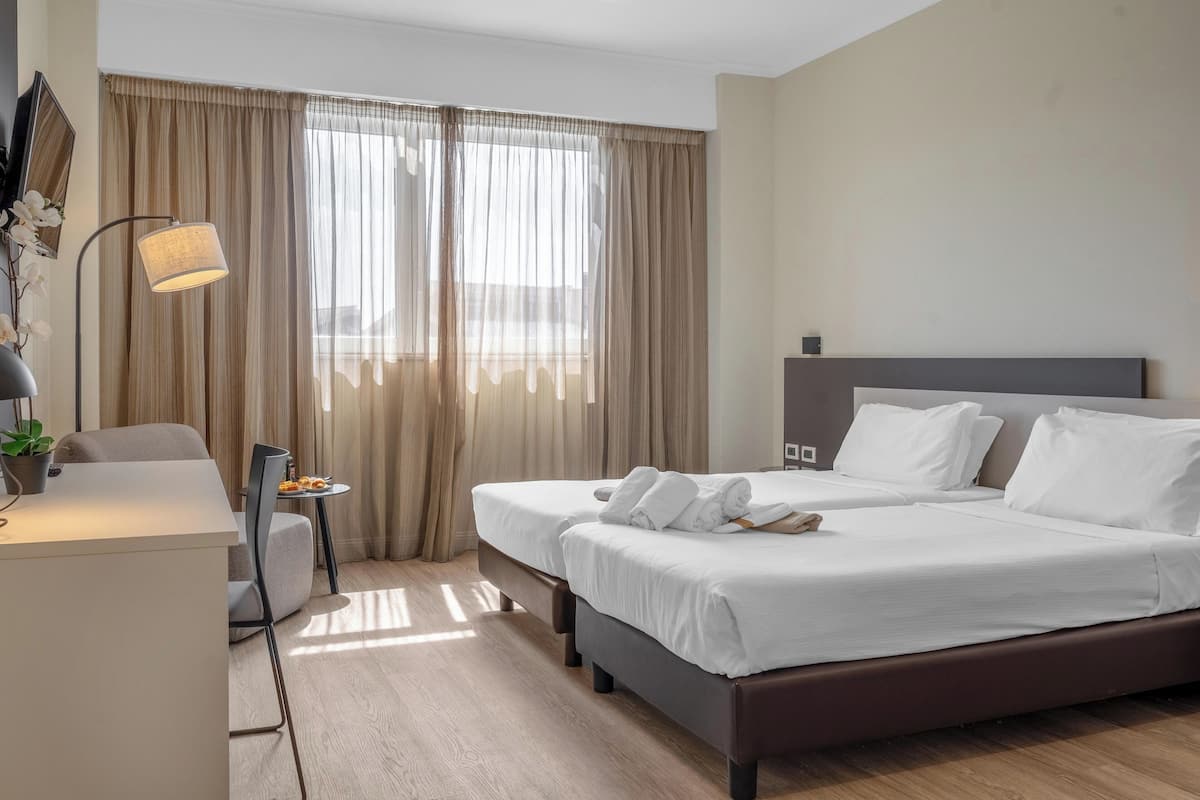 Ein Hotelzimmer mit Bett, Nachttischen, Schreibtisch, Stuhl und Lampe.