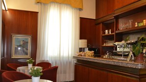 A hotel room with a dining area, a kitchen with a coffee machine, and a large window with curtains. - Hotel Residence (Parma)