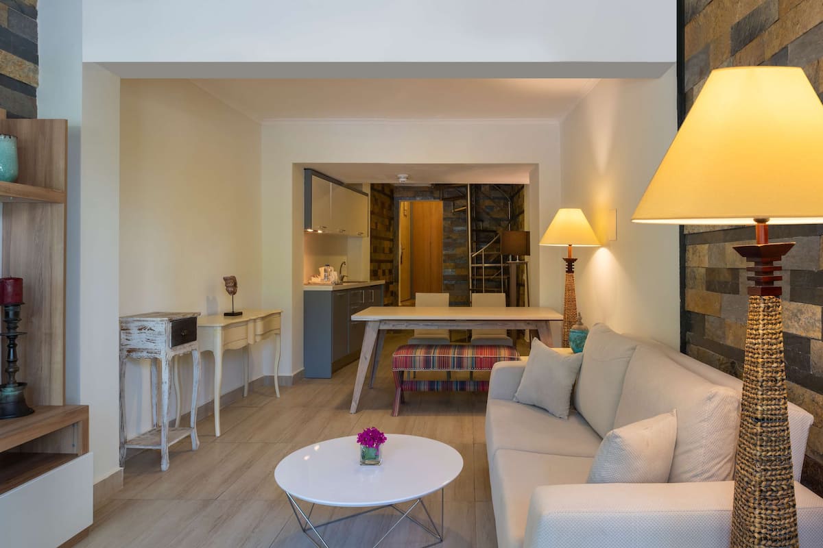 Una sala de estar moderna con un sofá, una mesa de centro, un televisor y una lámpara.
