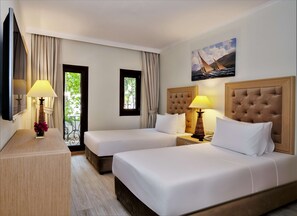 A hotel room with two beds, a wooden nightstand, a desk with a lamp, and a painting on the wall. - DoubleTree by Hilton Bodrum Marina Vista (Bodrum)