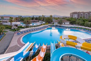 A large swimming pool with multiple slides, surrounded by lounge chairs and palm trees. - Asteria Family Resort Side (Ex. Euphoria Palm Beach) (Manavgat)