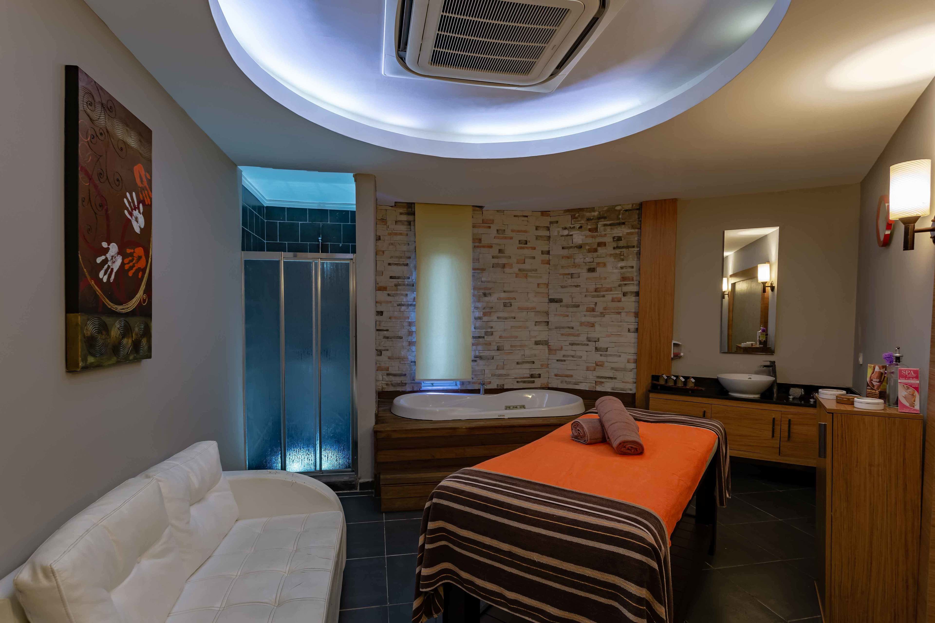 A modern bathroom with a bathtub, a massage table, and a shower area.