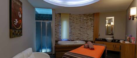 A modern bathroom with a bathtub, a massage table, and a shower area.