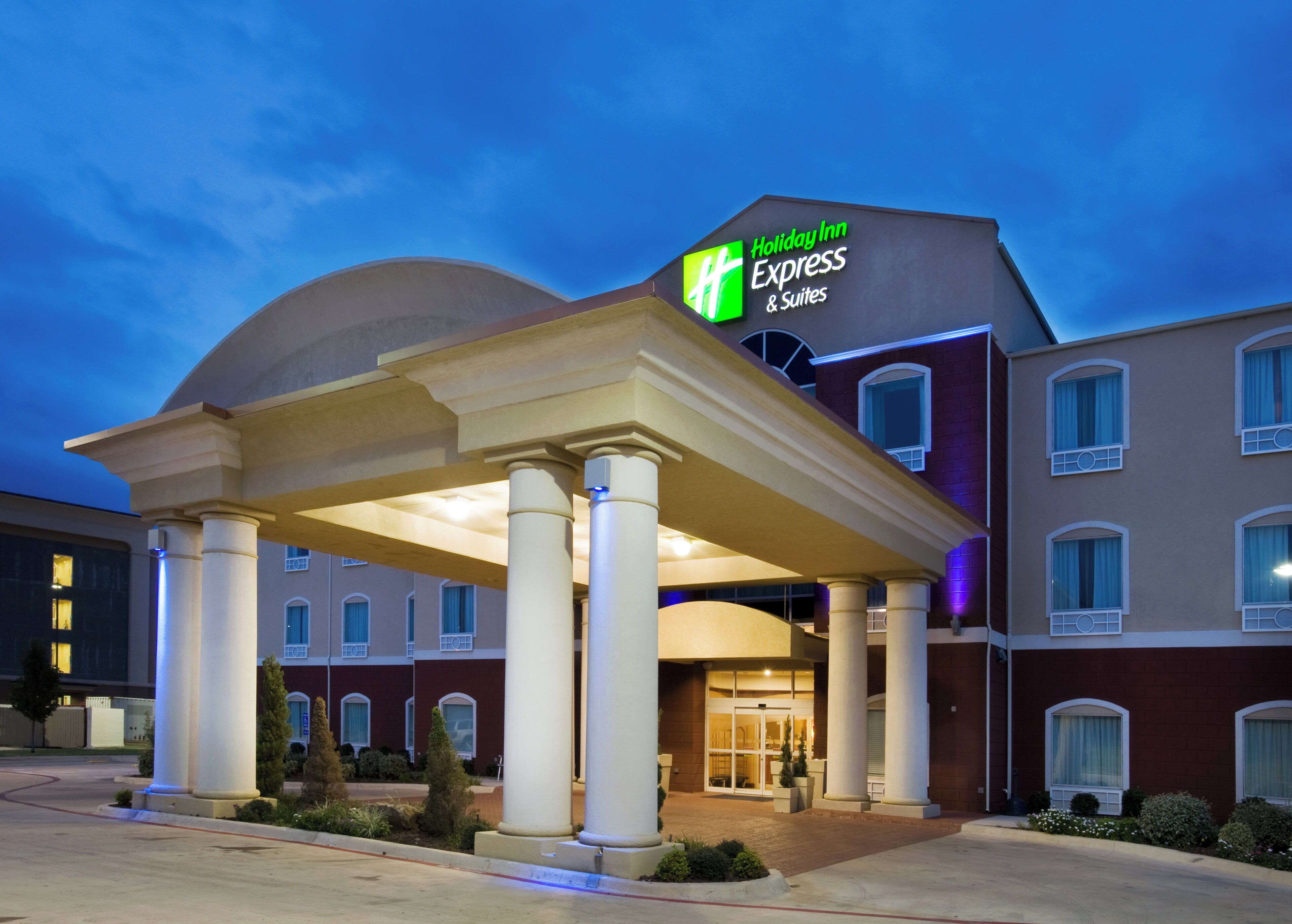 Un bâtiment de l’hôtel Holiday Inn Express & Suites, doté d’une entrée abritée et surplombant un ciel dégagé.