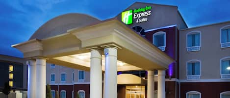 A Holiday Inn Express & Suites building with a covered entrance and a clear sky.