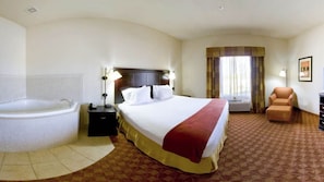 Quarto de hotel com uma cama grande, banheiro separado com banheira e uma cadeira.