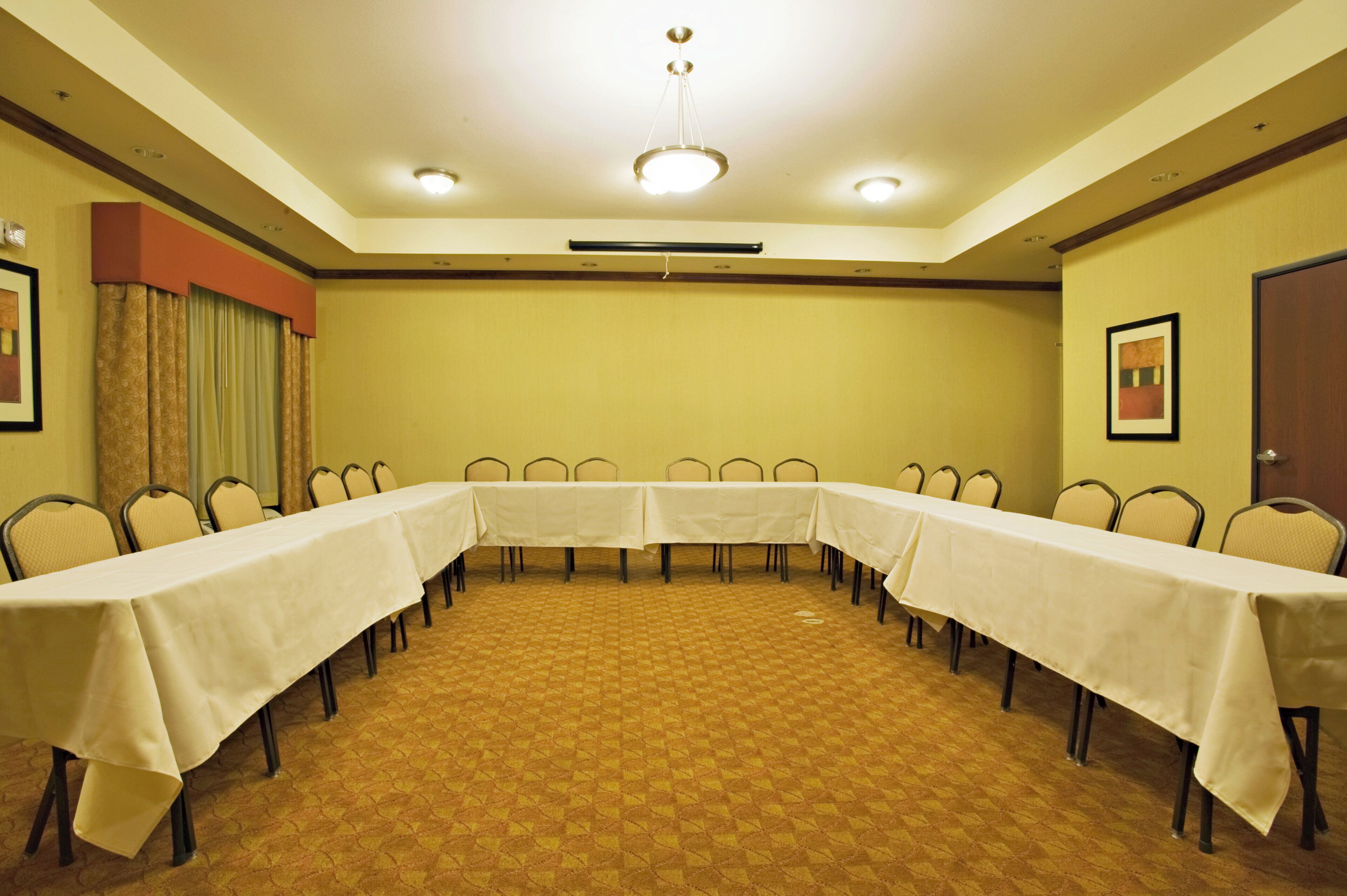 A conference room with a long table, chairs, and a carpeted floor.
