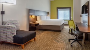 A hotel room with a bed, bedside tables, a desk, a chair, and a lamp. - Holiday Inn Express Hotel & Suites Charlotte Arrowood by IHG (Charlotte)