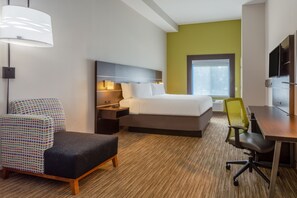Quarto de hotel com cama, mesas de cabeceira, escrivaninha, cadeira e luminária.