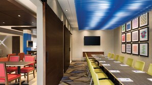 A conference room with a long table and yellow chairs, a blue ceiling, and framed artwork on the wall. - Holiday Inn Express Hotel & Suites Charlotte Arrowood by IHG (Charlotte)