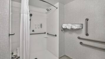 A modern bathroom with a walk-in shower, grab bars, and a towel rack.