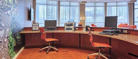A hotel reception area with a curved desk, two office chairs, a printer, and a television.