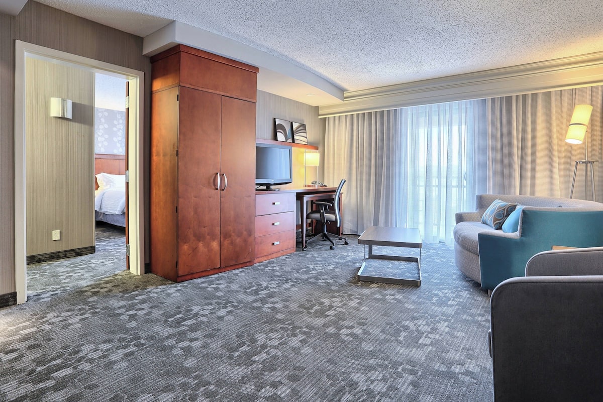 Une chambre d’hôtel avec une grande armoire, un bureau avec un ordinateur, un canapé et un lit.