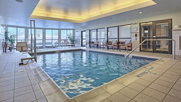 An indoor swimming pool with clear water, surrounded by seating areas and large windows. - Courtyard by Marriott Harrisburg West/Mechanicsburg (Mechanicsburg)