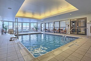 Una piscina interior con agua cristalina, rodeada de zonas de descanso y grandes ventanales.