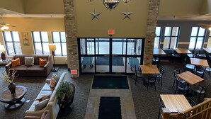 A spacious lobby with a chandelier, seating area, and large windows.