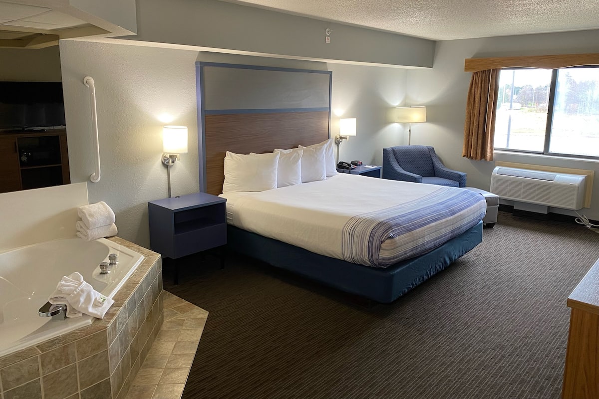 Habitació d'hotel amb un llit gran, un bany separat amb banyera, una taula de treball i una cadira.