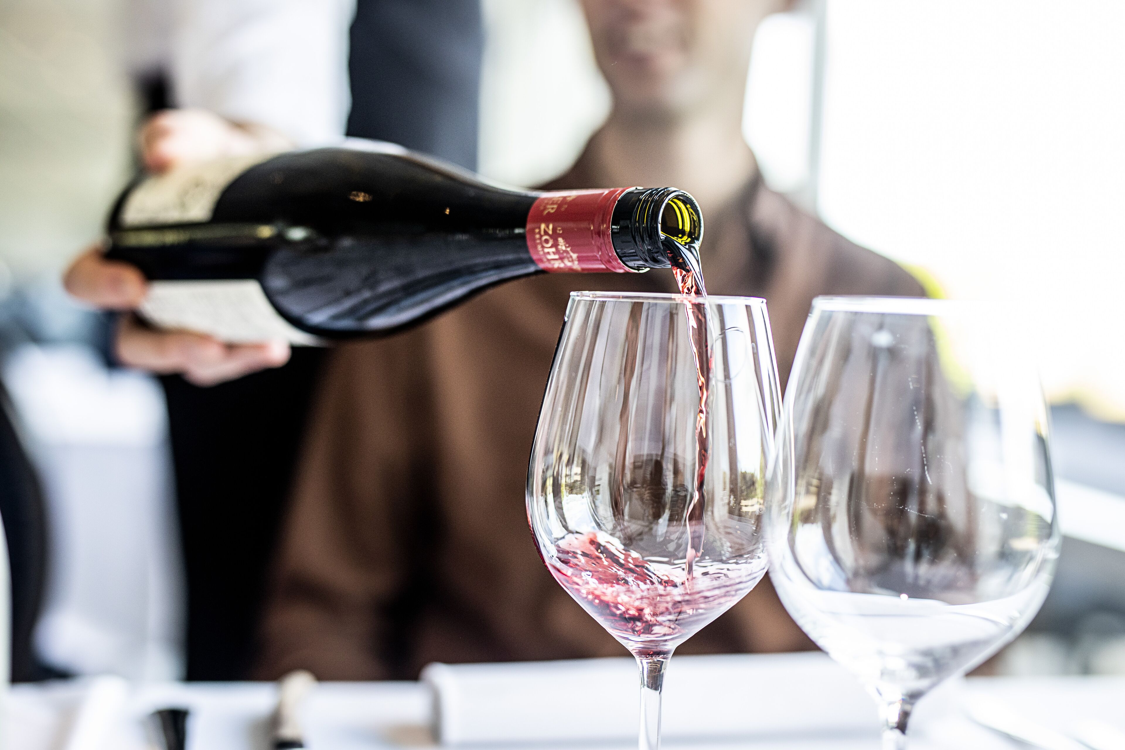 A bottle of wine being poured into a glass.