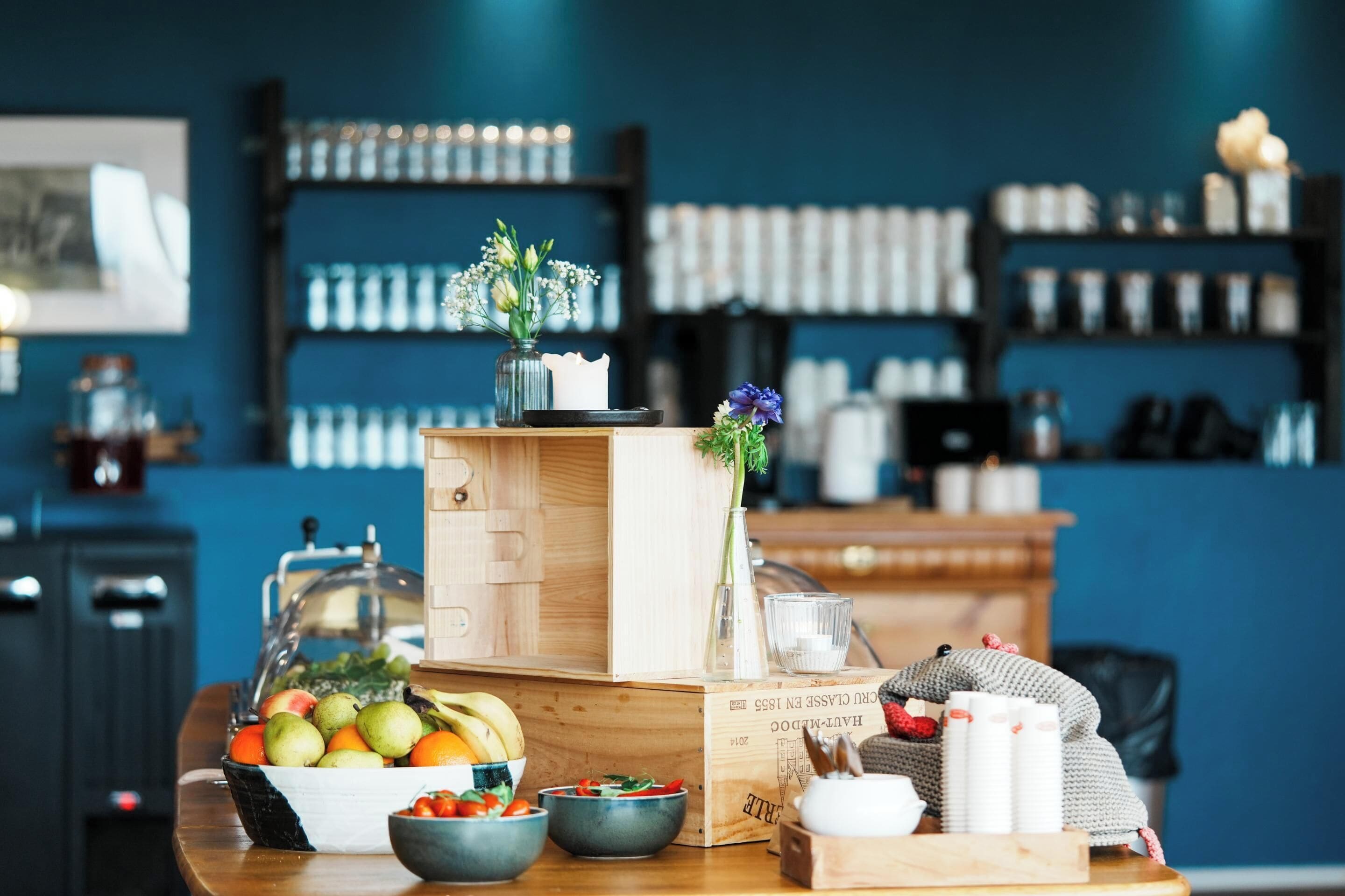 A breakfast setup with fruits, a vase with flowers, and a coffee machine.
